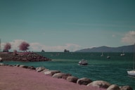 Boats and trees sit along the coast under a partly cloudy sky, with the colors pushed slightly unreal.