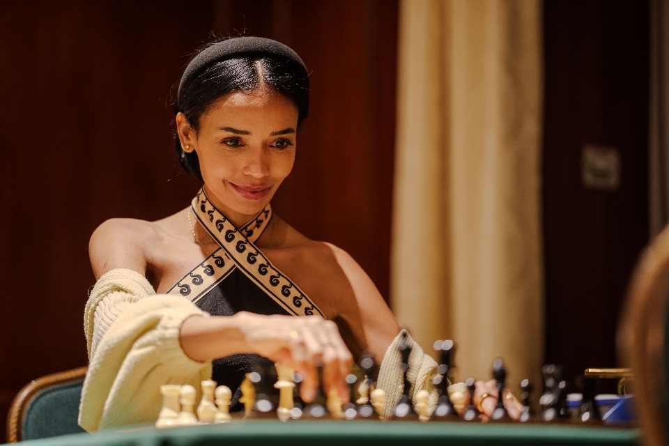 A woman plays chess, her focused expression highlighting the strategic depth of the game.